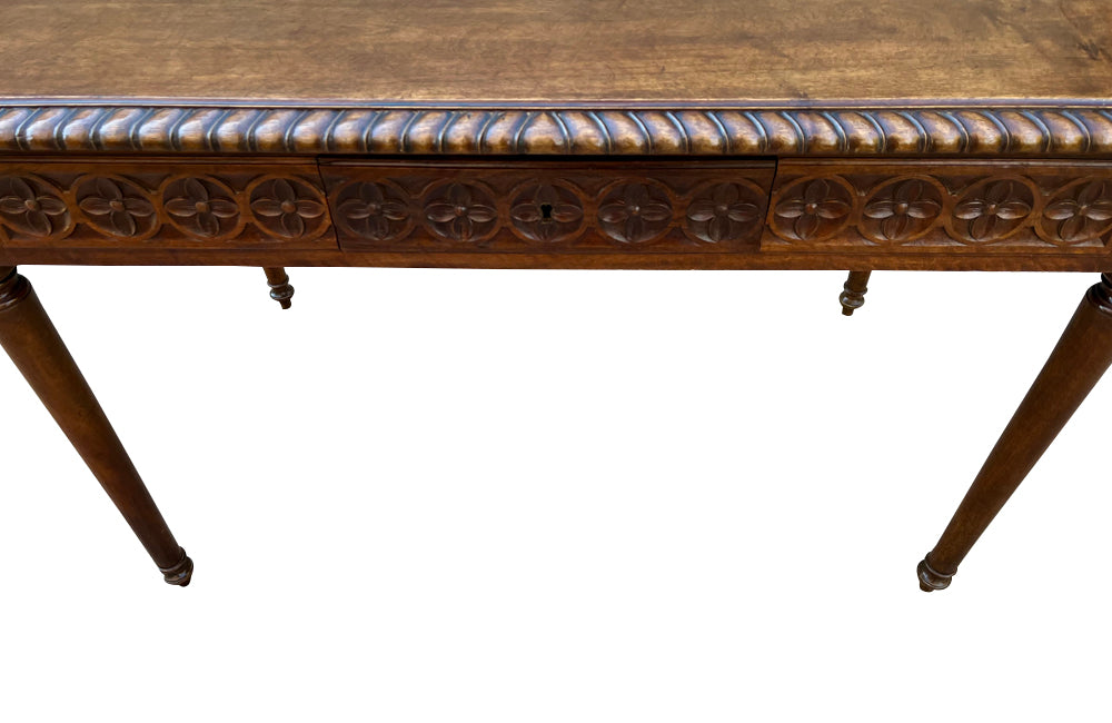 19th century walnut desk decorated with carved with Neo-Classical motifs to all sides.