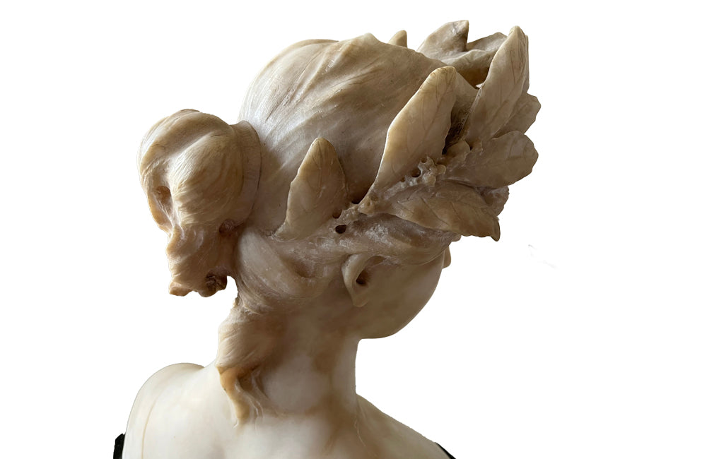 20th Century marble bust of a serene young woman with laurel wreath in hair and fine robe. 
