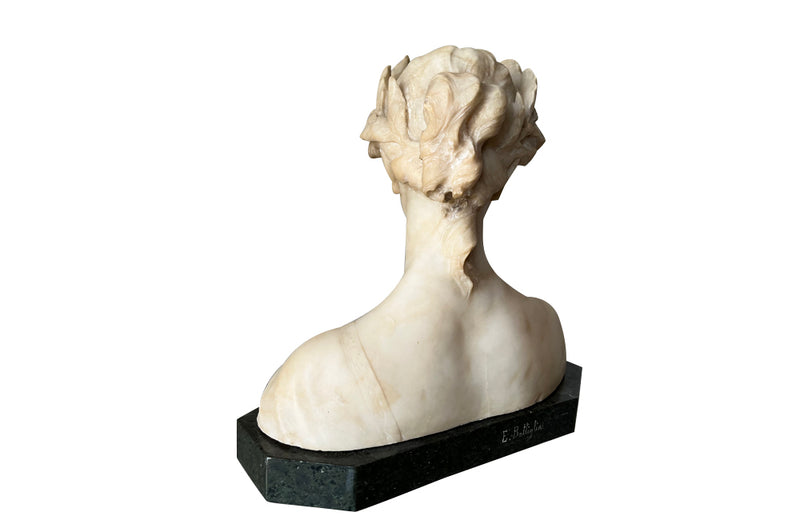 20th Century marble bust of a serene young woman with laurel wreath in hair and fine robe. 
