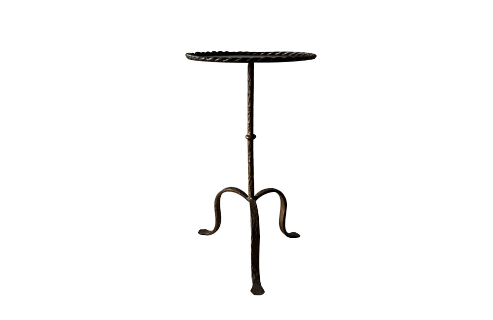 Spanish, gilt iron cocktail table with hammered and rope rim top on hammered ringed stem and decoratively shaped tripod base.