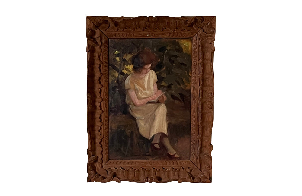 Charming framed oil on wood painting of a seated young woman reading in her garden .