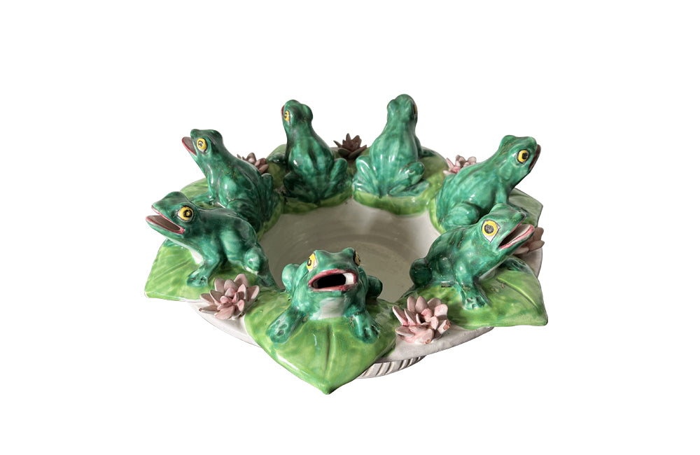20th century glazed terracotta centrepiece in the form of a basket with seven open mouthed frogs on flowering water lily pads surrounding the rim.