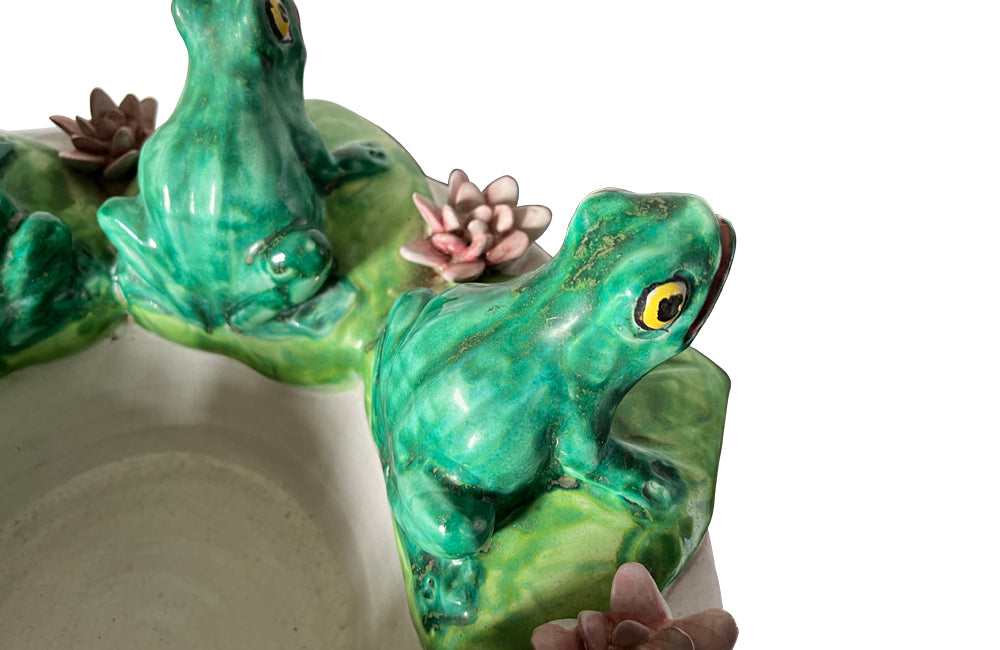 20th century glazed terracotta centrepiece in the form of a basket with seven open mouthed frogs on flowering water lily pads surrounding the rim.