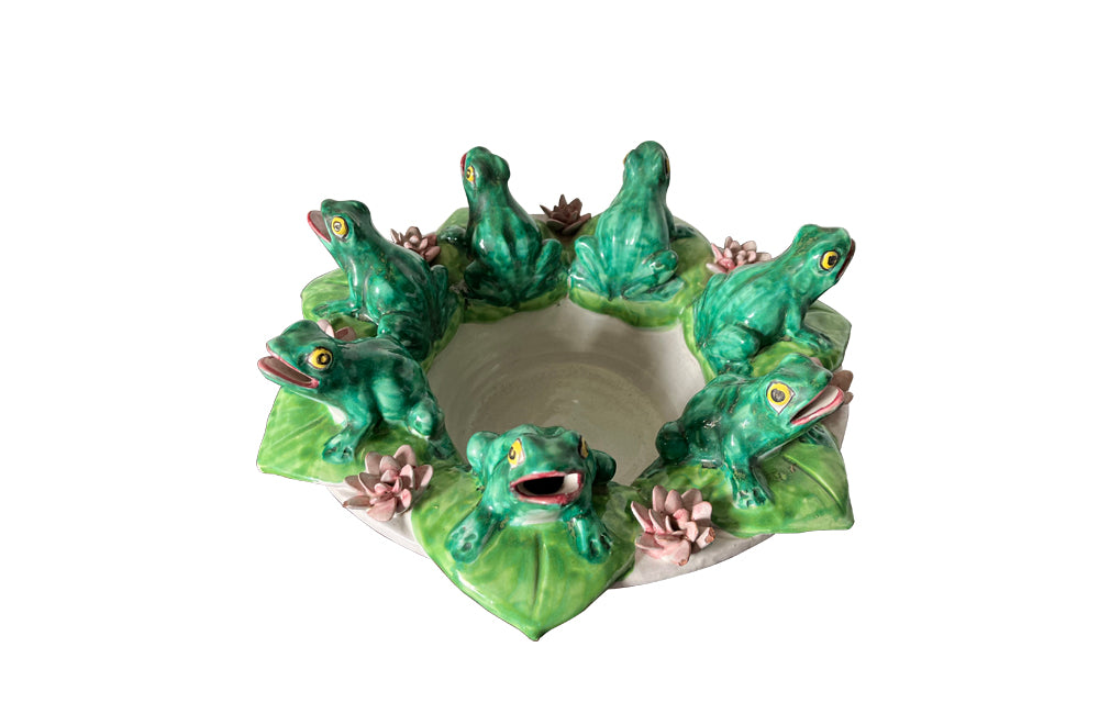 20th century glazed terracotta centrepiece in the form of a basket with seven open mouthed frogs on flowering water lily pads surrounding the rim.