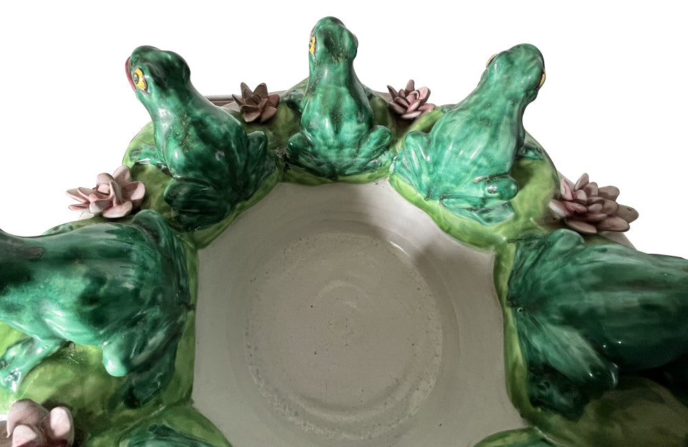 20th century glazed terracotta centrepiece in the form of a basket with seven open mouthed frogs on flowering water lily pads surrounding the rim.