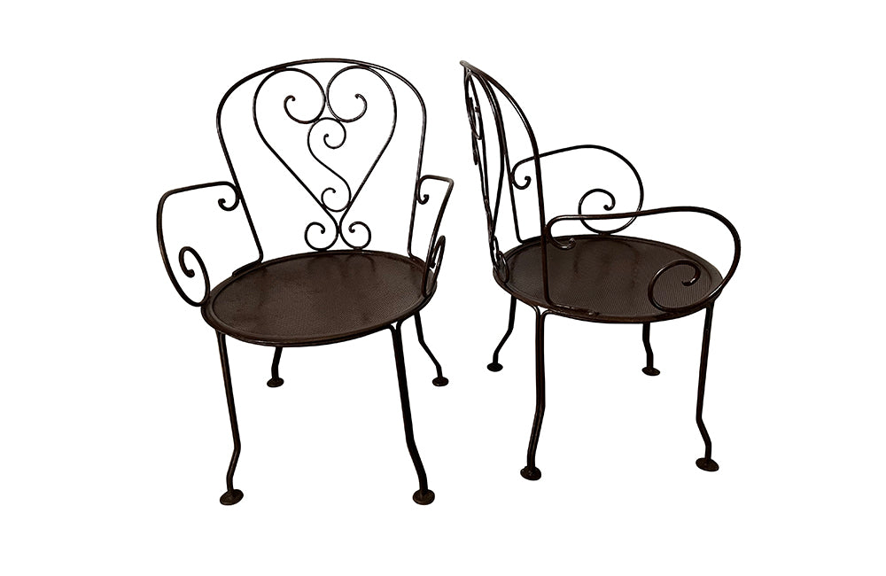 set of four French antique wrought iron garden chairs, comprising two armchairs and two chairs. Each has lovely scrolled ironwork and pierced iron seats. Circa 1900