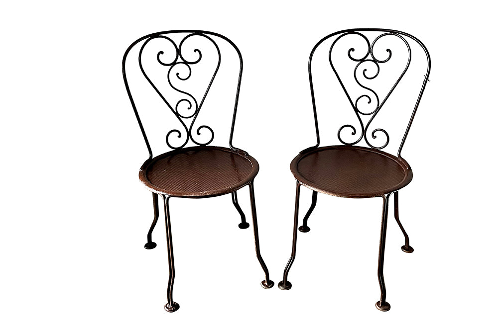 set of four French antique wrought iron garden chairs, comprising two armchairs and two chairs. Each has lovely scrolled ironwork and pierced iron seats. Circa 1900