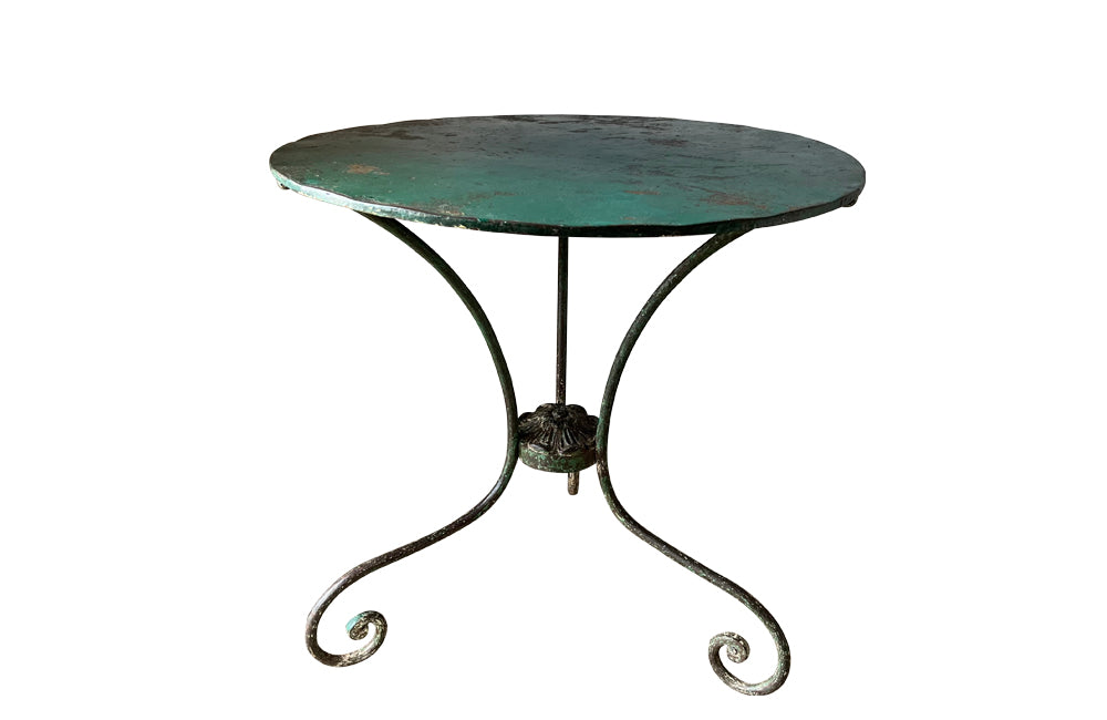 French green iron gueridon with lovely scrolled wrought iron legs and pretty cast iron central floral medallion. Remains of its original layers of paint.