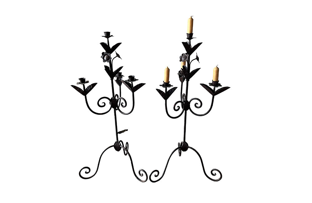 Pair of large wrought iron candle holders from a chateau in the Dordorgne. Tall decorative candlesticks with floral and foliate decoration and have 4 candle holders.