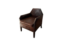 Antique club chair leather with embossed back featuring a putti and scrolled foliate decoration. France.