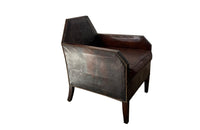 Antique club chair leather with embossed back featuring a putti and scrolled foliate decoration. France.