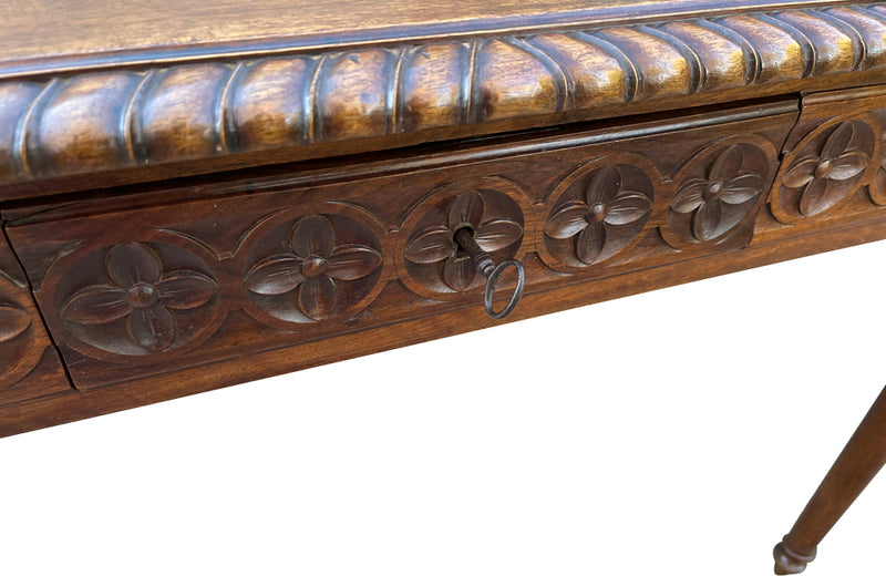 19th century walnut desk decorated with carved with Neo-Classical motifs to all sides.