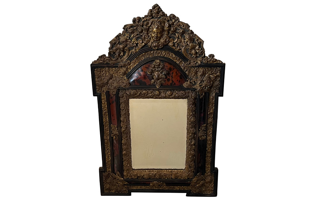 Antique mirror Louis XIV style French with faux tortoiseshell veneer and repousee brass decoration. Richly decorated with floral, foliate and fruit motif.
