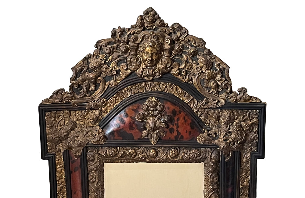 Antique mirror Louis XIV style French with faux tortoiseshell veneer and repousee brass decoration. Richly decorated with floral, foliate and fruit motif.