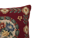 19th Century French needlepoint pillow featuring a classic floral wreath medallion on a deep burgundy ground.