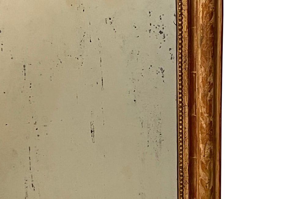 Antique mirror French Louis Philippe giltwood 19th Century with beaded inner surround and Neo-Classical foliate decoration to the frame.