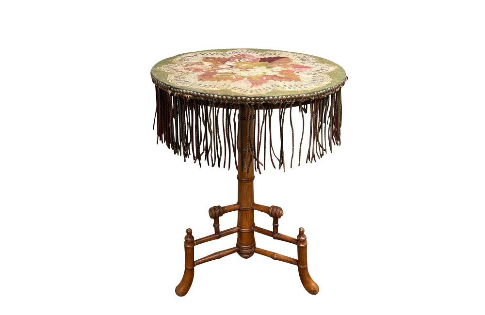 Charming 19th century faux bamboo occasional table with worn tapestry fabric top and decorative fringed surround.