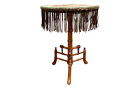 Charming 19th century faux bamboo occasional table with worn tapestry fabric top and decorative fringed surround.