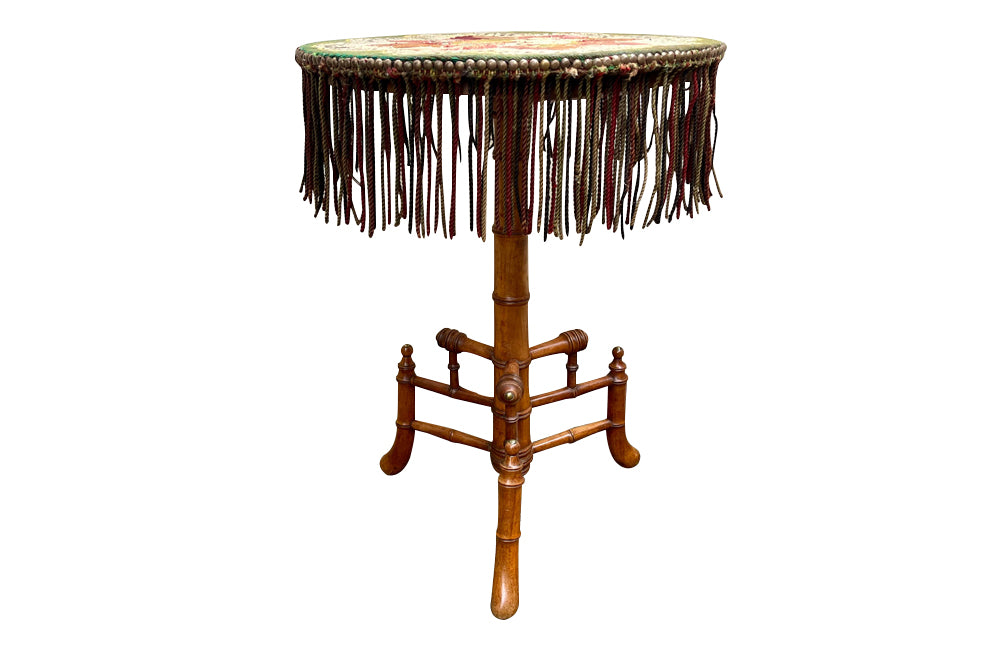Charming 19th century faux bamboo occasional table with worn tapestry fabric top and decorative fringed surround.