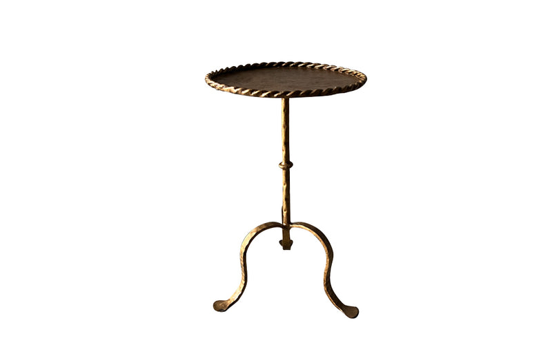 Chic, Spanish, gilt iron cocktail table with hammered and rope rim top on hammered ringed stem and decoratively shaped tripod base.