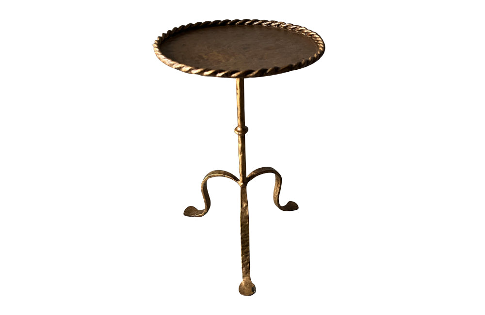 Chic, Spanish, gilt iron cocktail table with hammered and rope rim top on hammered ringed stem and decoratively shaped tripod base.