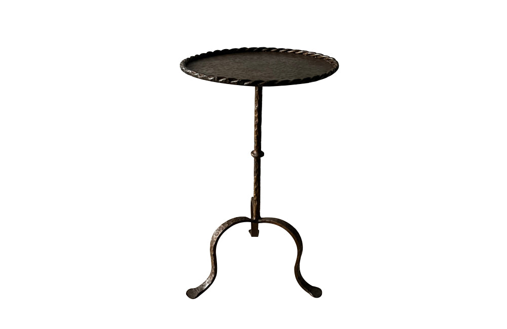 Spanish, gilt iron cocktail table with hammered and rope rim top on hammered ringed stem and decoratively shaped tripod base.