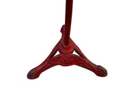 A pedestal table with a distressed red cast iron tripod base and a circular marble top 