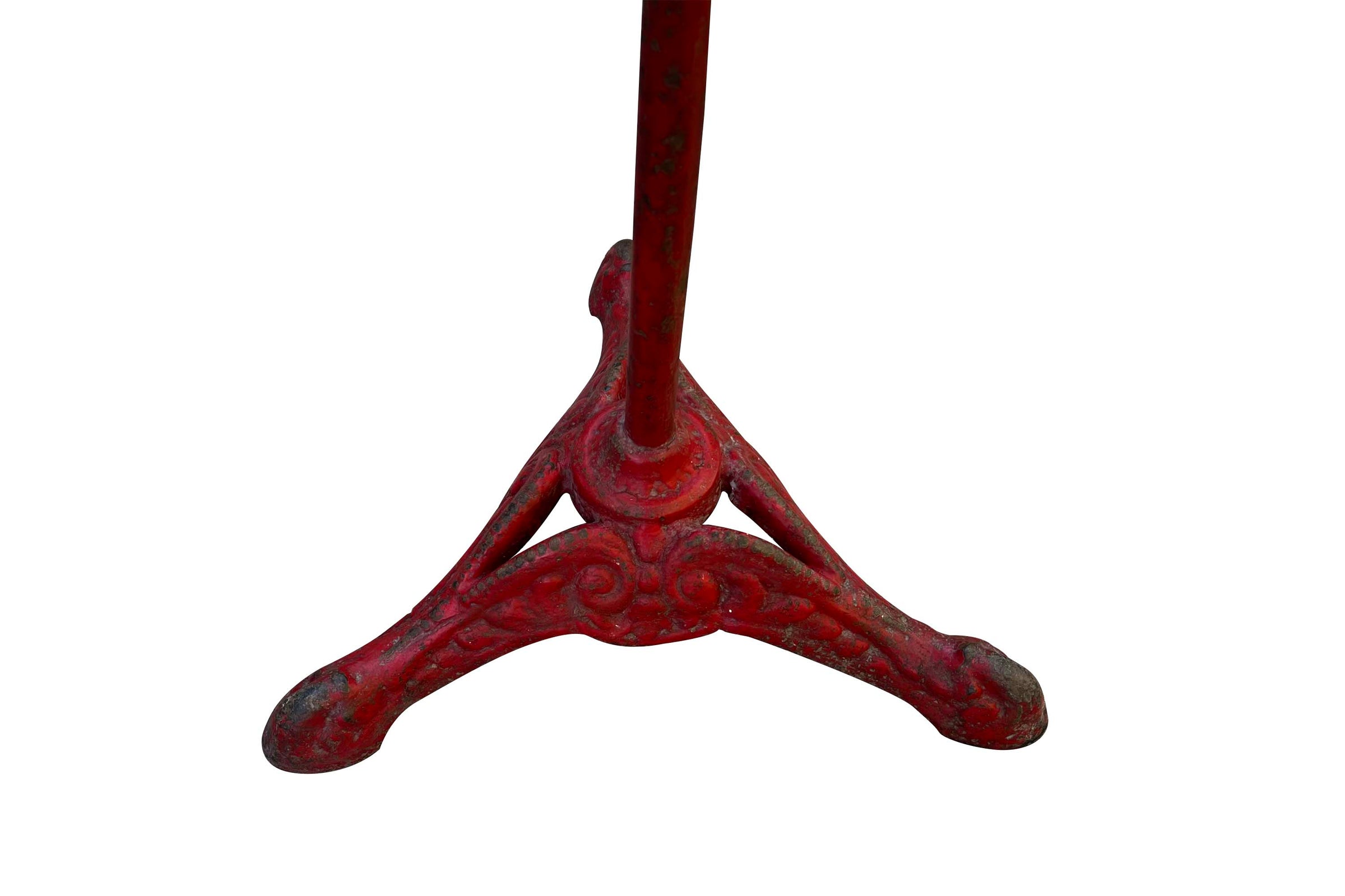 A pedestal table with a distressed red cast iron tripod base and a circular marble top 