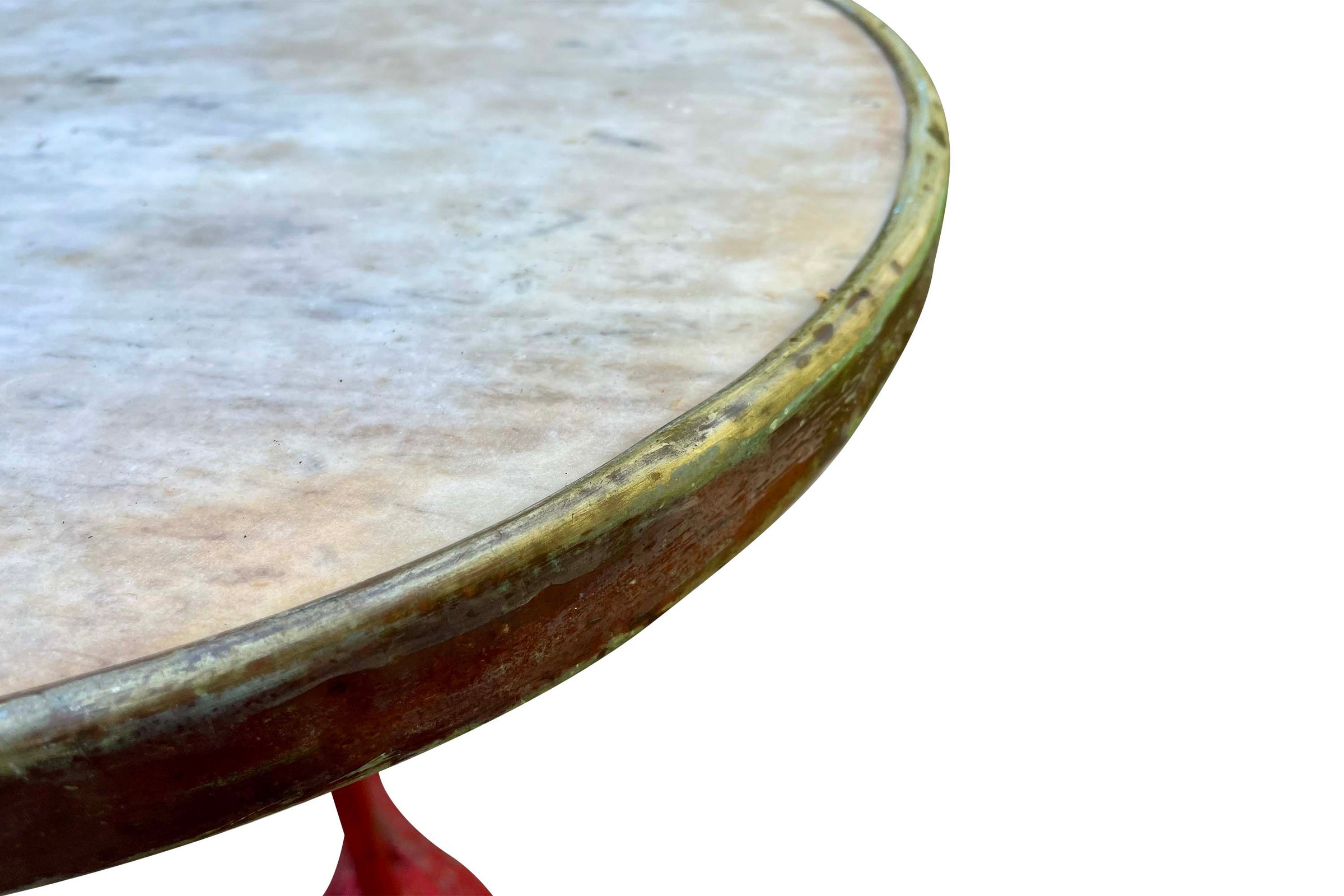 A pedestal table with a distressed red cast iron tripod base and a circular marble top 