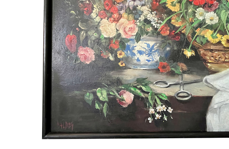 19th Century still life painting of flowers in a florist setting with draped table and backdrop. This joyous oil on canvas has been beautifully relined and framed in a simple black frame. It is signed Valdeg - AD & PS Antiques