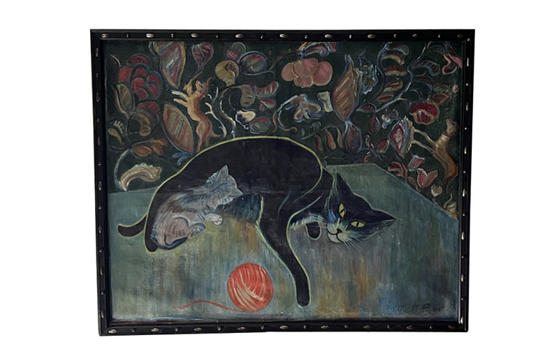 Large 20th Century framed oil on canvas painting of a reclining black cat with her kitten and a ball of wool on a table. 