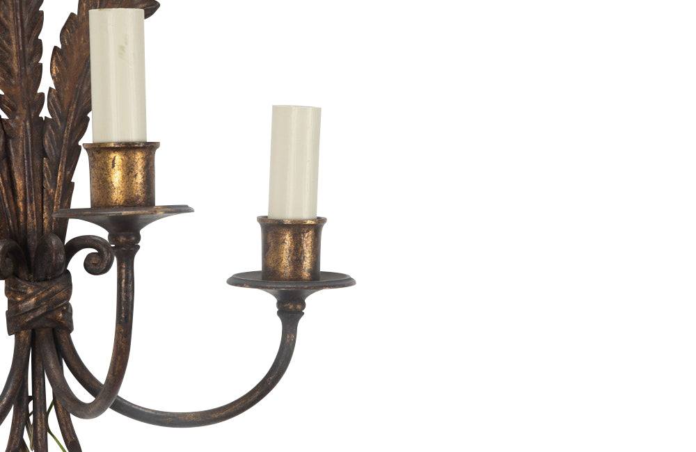 Metal wall light with three tied ostrich feathers and three branched arm bulb holders.