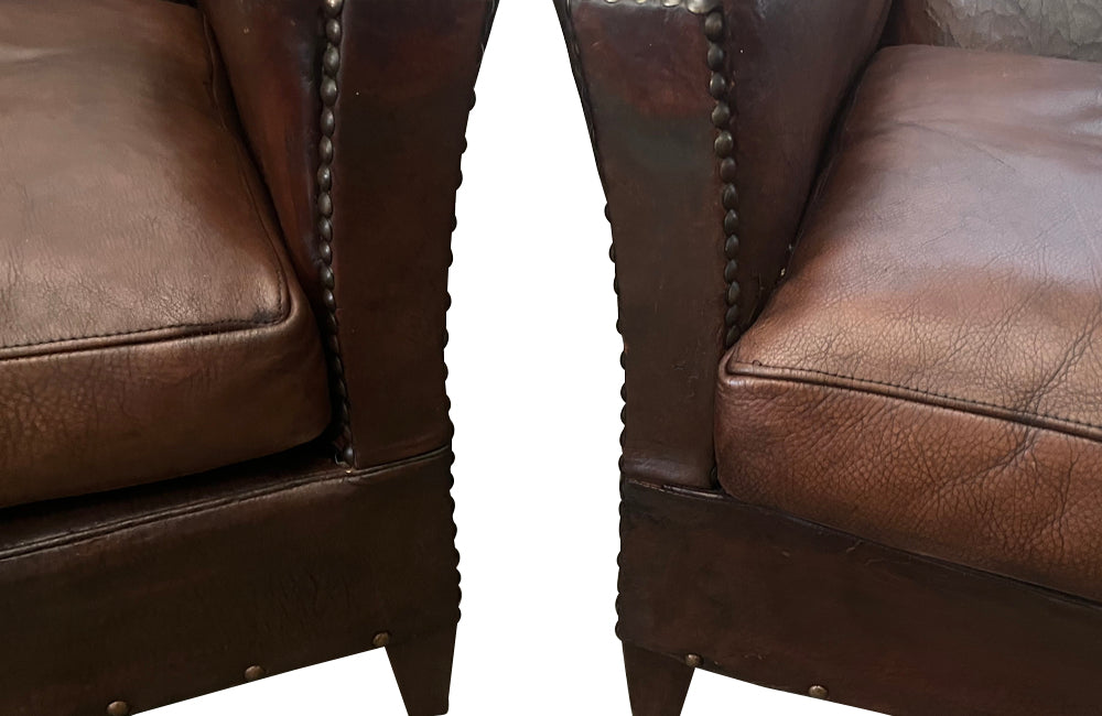 Charming pair of small 1920s French leather club chairs with squared backs and splayed arms.