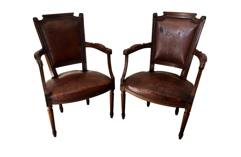 Elegant pair of 20th Century French comfortable worn leather armchairs in the Louis XVI style.