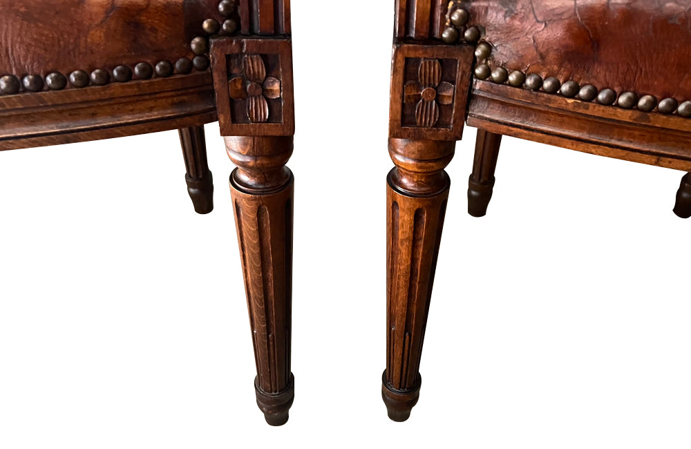 Elegant pair of 20th Century French comfortable worn leather armchairs in the Louis XVI style.