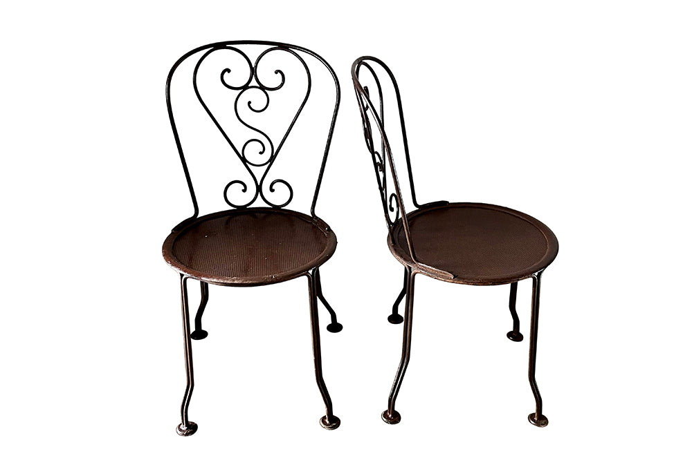set of four French antique wrought iron garden chairs, comprising two armchairs and two chairs. Each has lovely scrolled ironwork and pierced iron seats. Circa 1900