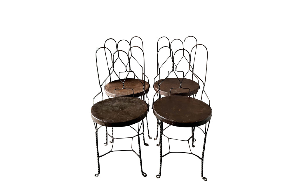 An elegant set of four mid-20th Century French wrought-iron folding chairs of the 'Bouchon de Champagne' type.