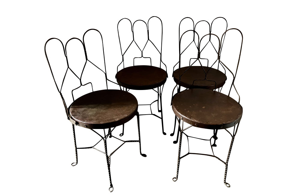 An elegant set of four mid-20th Century French wrought-iron folding chairs of the 'Bouchon de Champagne' type.