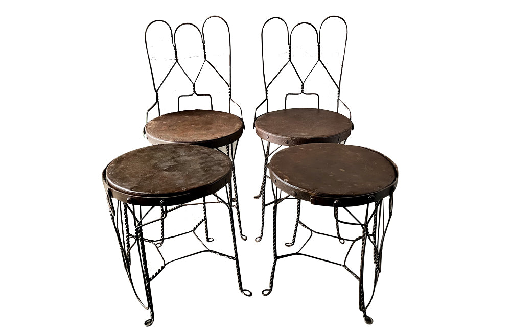 An elegant set of four mid-20th Century French wrought-iron folding chairs of the 'Bouchon de Champagne' type.