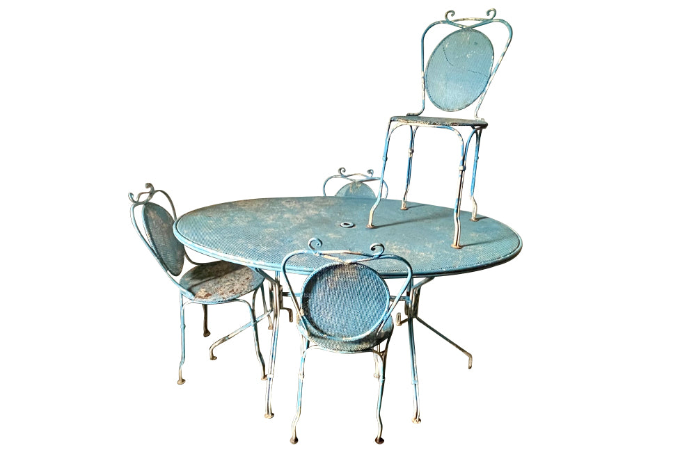 Large French mid century oval pierced iron garden table and it's matching four chairs.